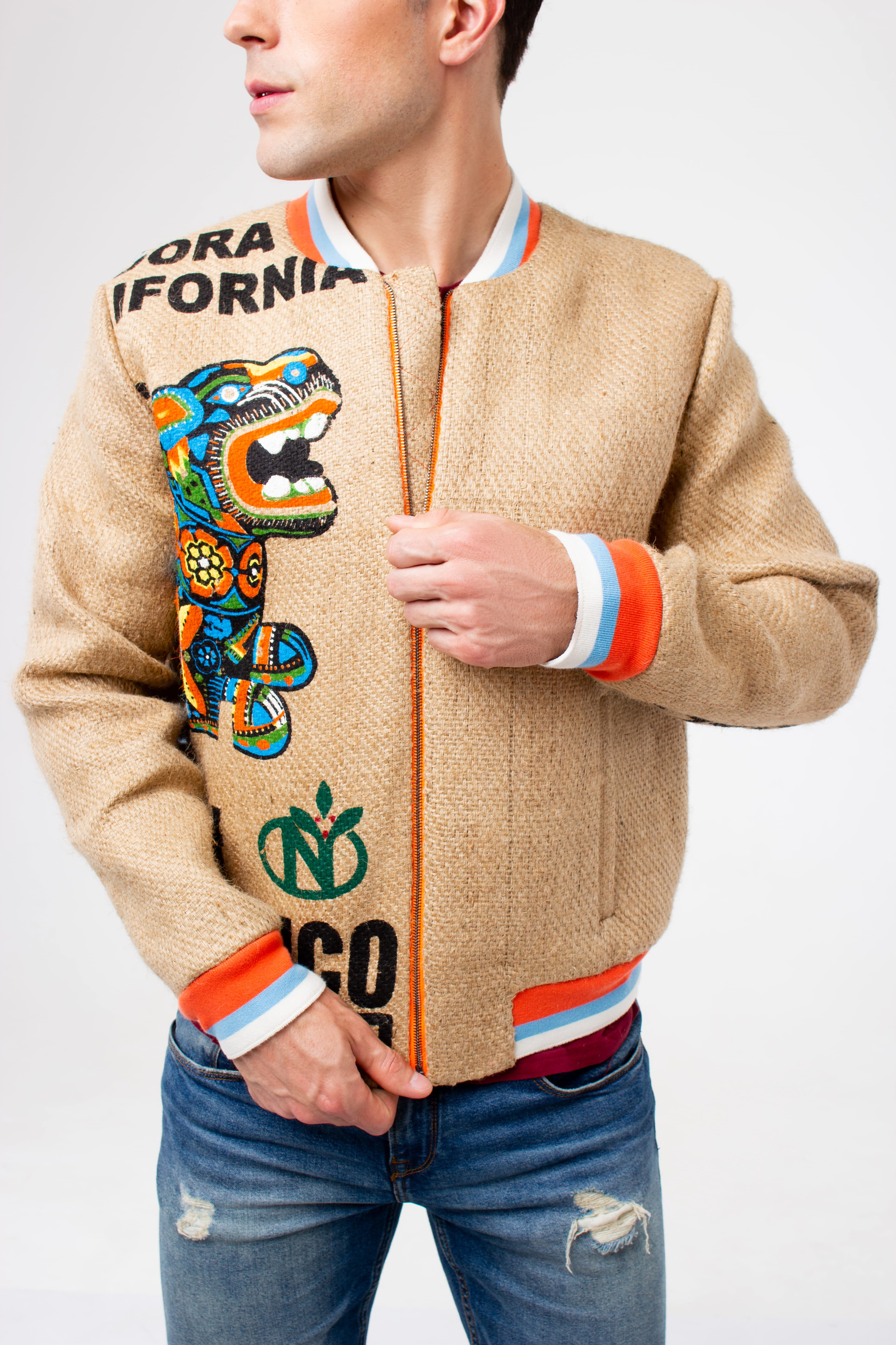 A young man pulling up an orange titanium zipper of his one-off eco jacket made of upcyceled coffee sacks